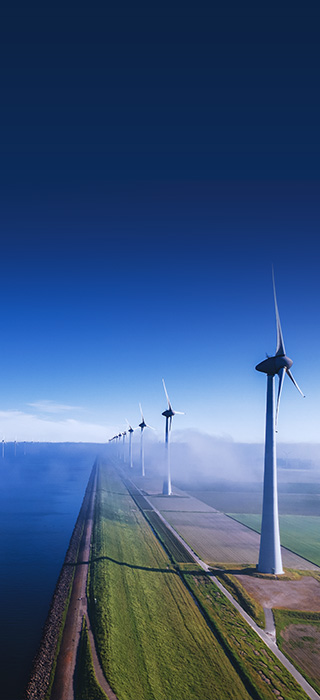 Aerial photo presenting wind turbines located both on land and close to the shoreline in the sea.