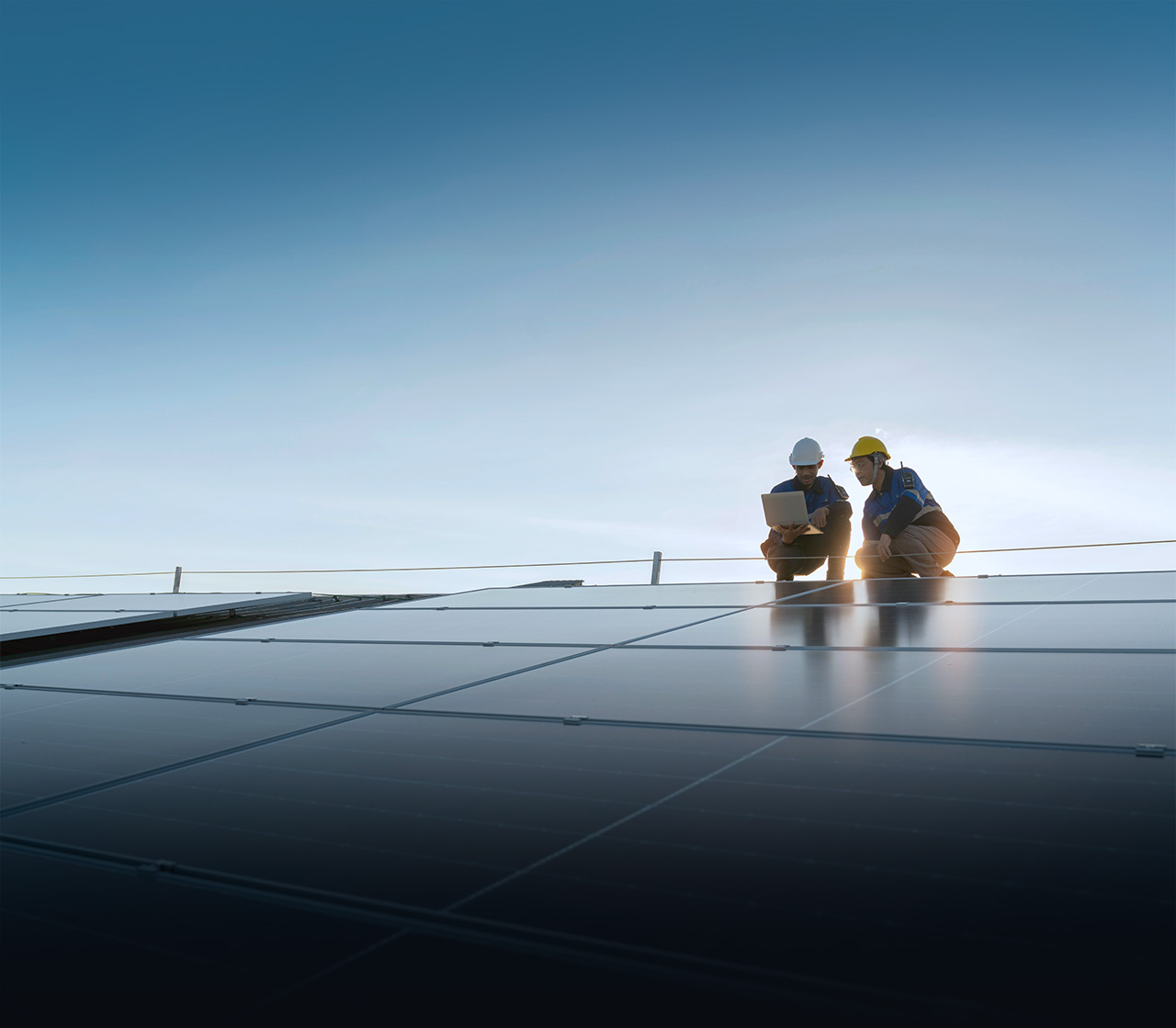 Two solar panel technicians taking measurements of effeciency of panel farm.